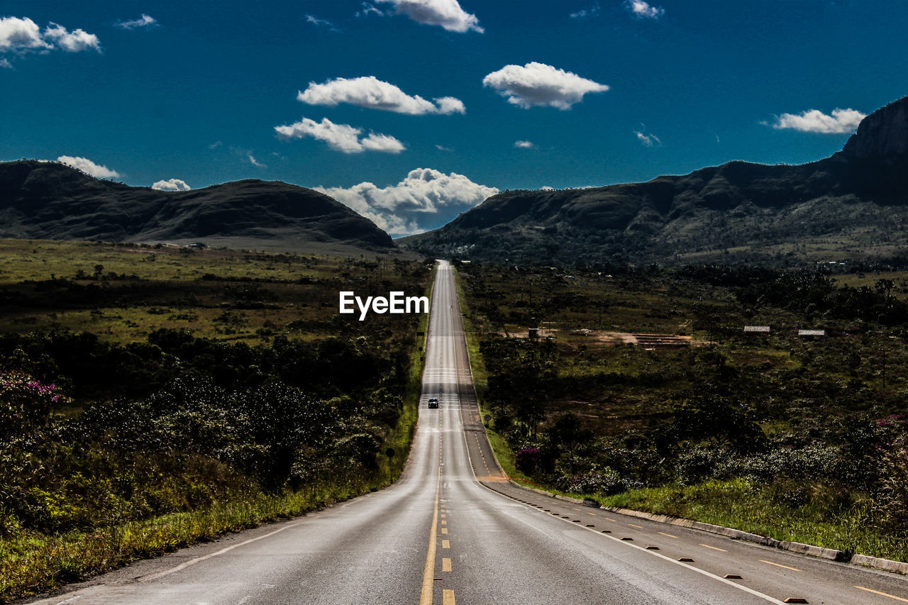 Road leading towards mountains against sky