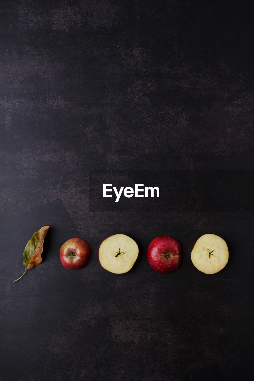 Flat lay autumn mood. fallen leaf and apples on a dark concrete background