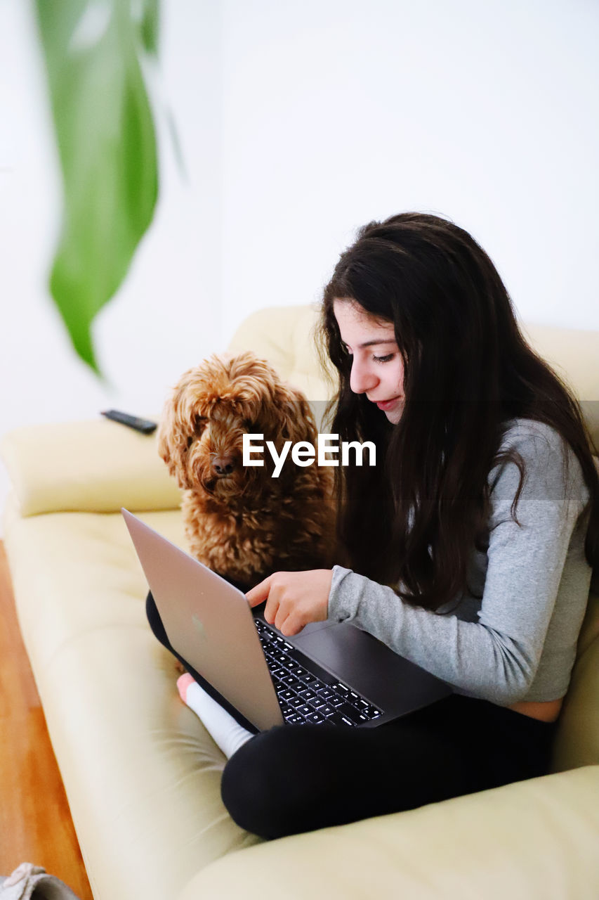 YOUNG WOMAN WITH DOG SITTING ON FLOOR