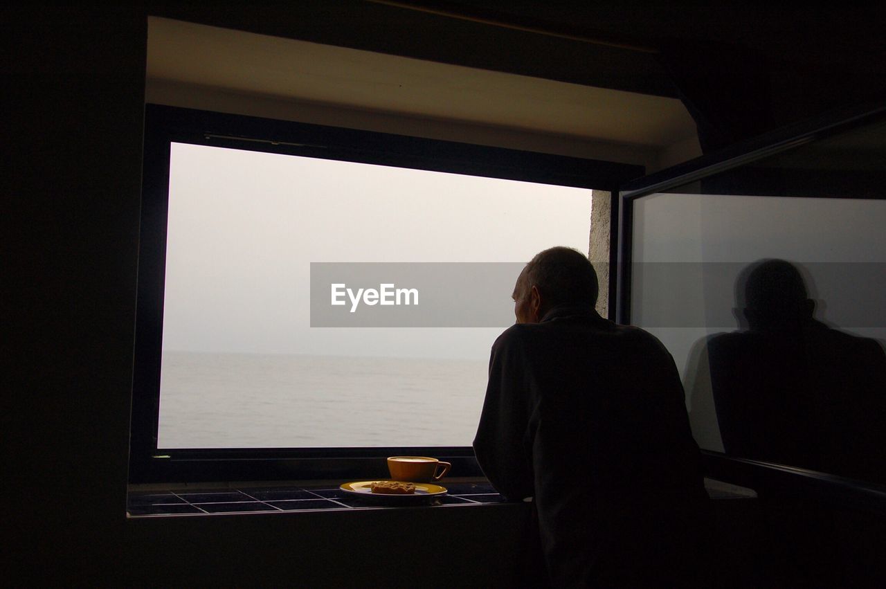 Rear view of man standing by window in boat