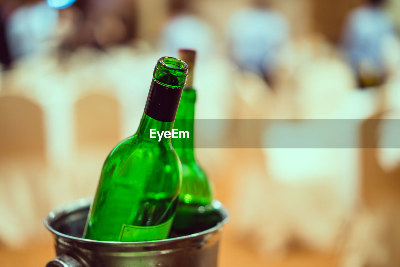 Close-up of empty green bottles in metallic bucket