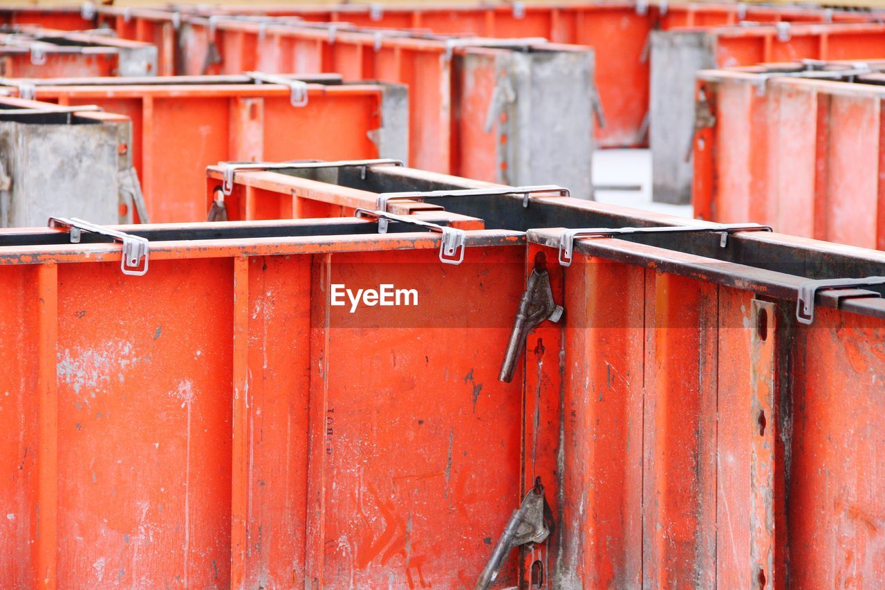 Close-up of rusty metal gate against red wall