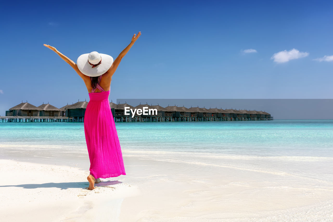 Full length of woman walking at beach against sky