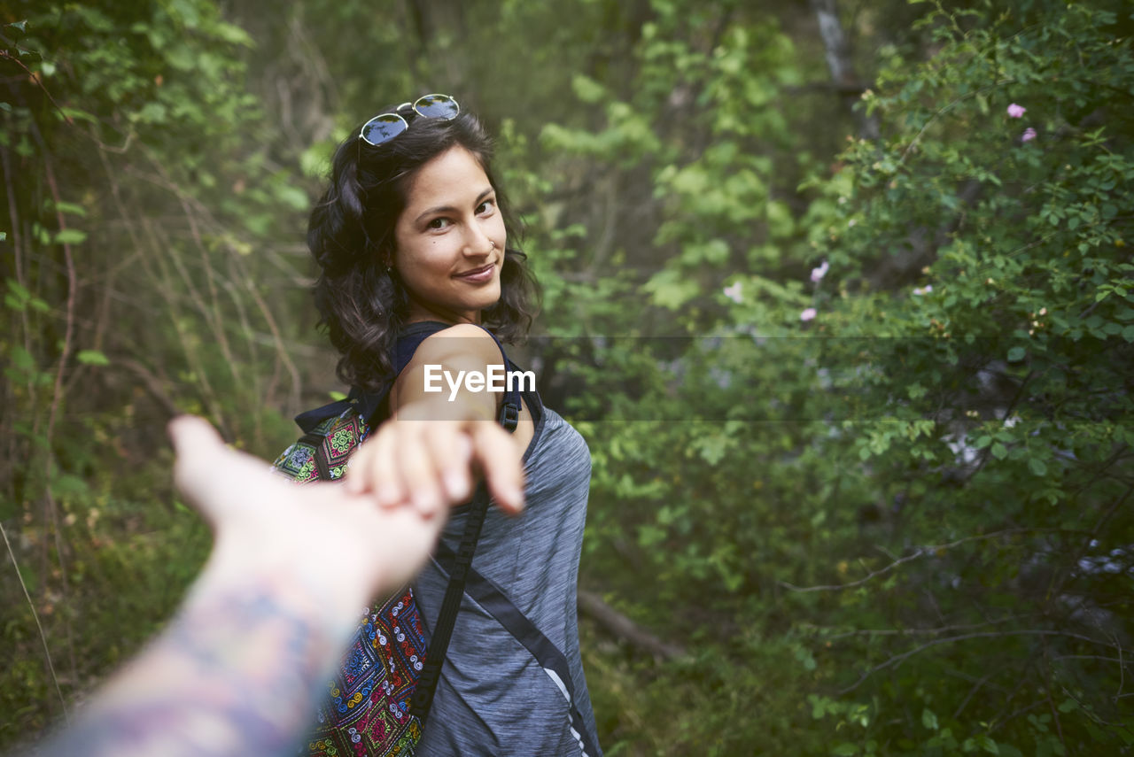 Portrait of a happy young woman holding her boyfriend's hand as she walks down the mountain