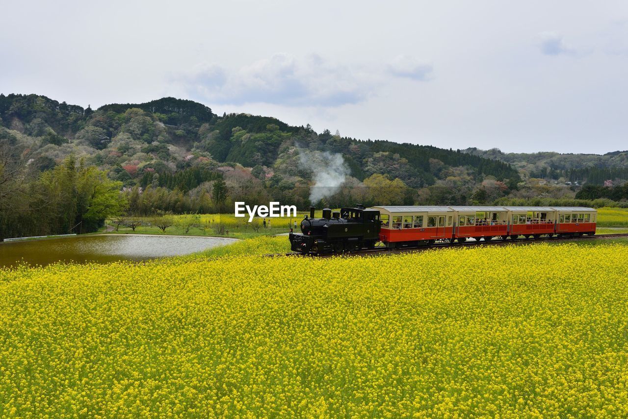 Train on railroad track amidst field against sky