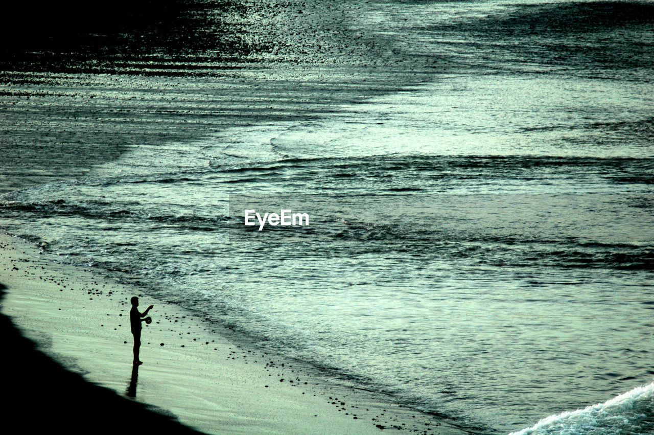 SILHOUETTE OF MAN STANDING ON BEACH