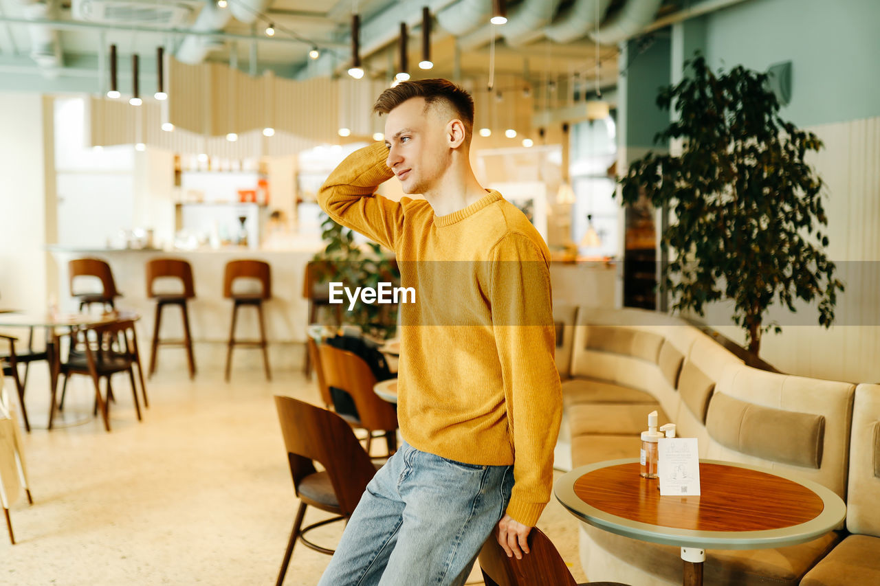 A young man freelance businessman uses wireless technology while working while sitting in a cafe