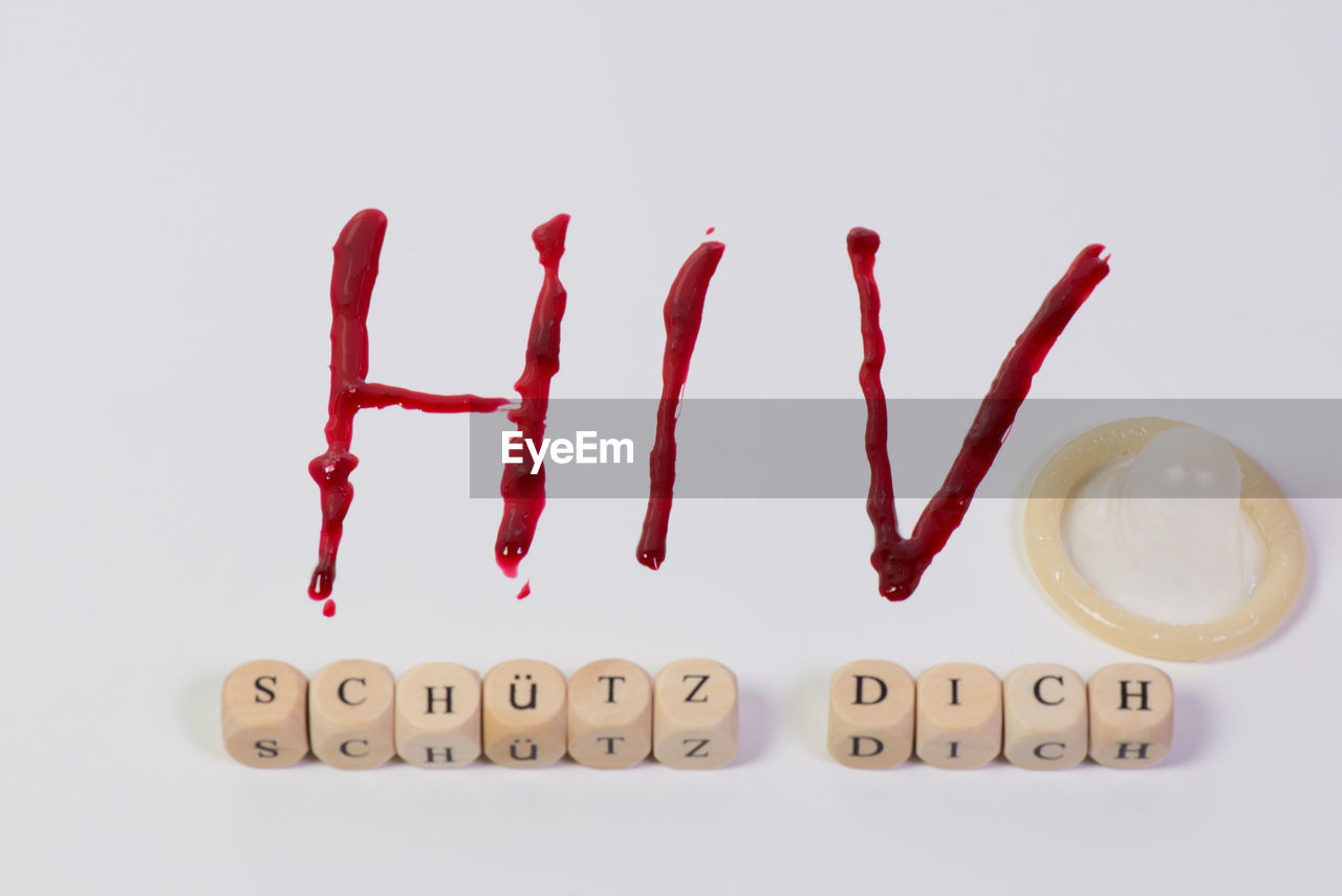 Close-up of text in blood and condom over white background