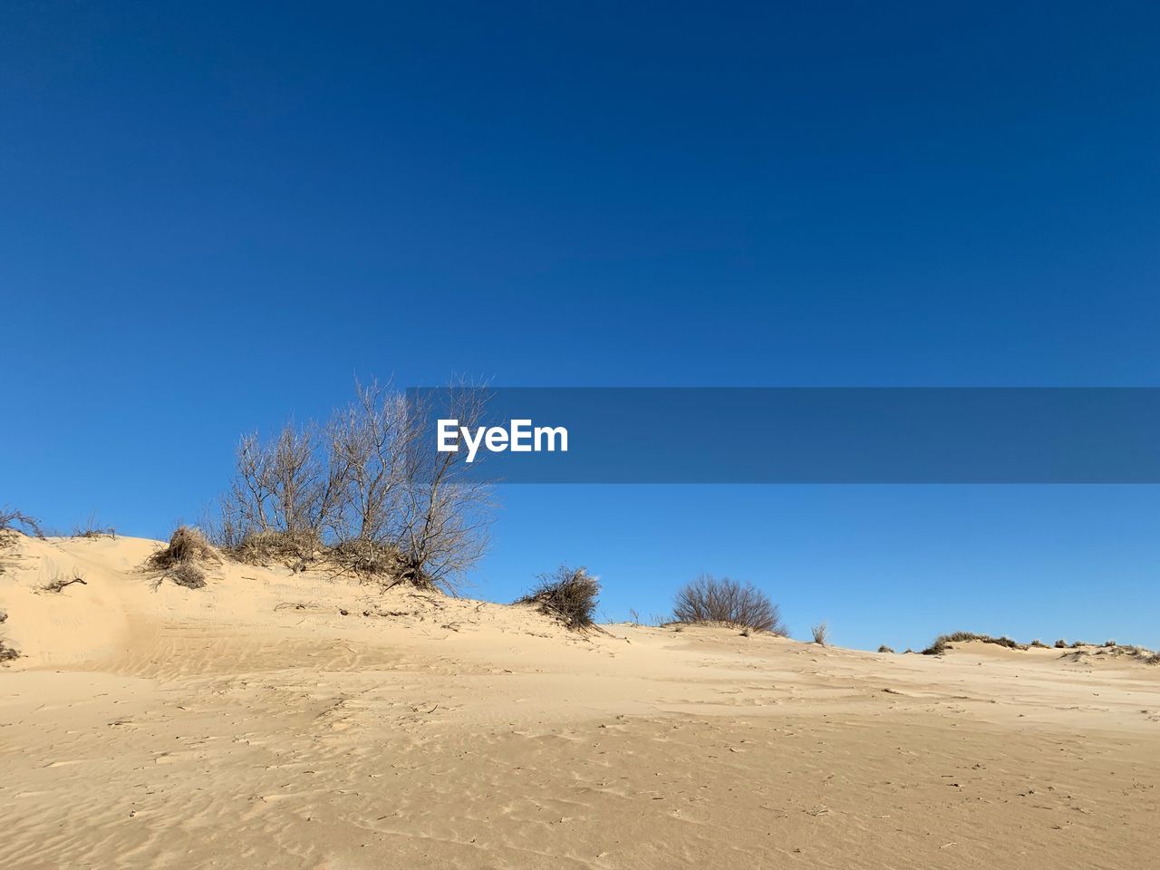 Scenic view of desert against clear blue sky