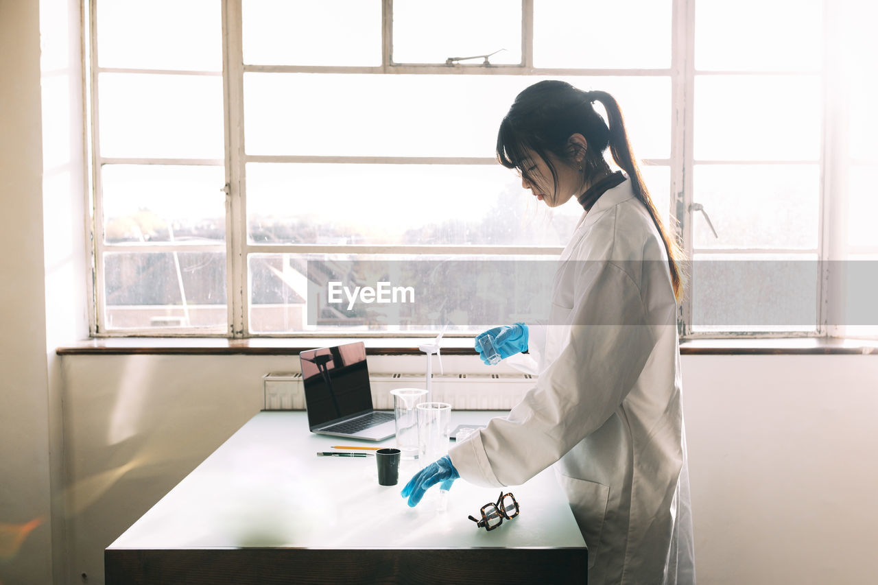 Young scientist working on table near window