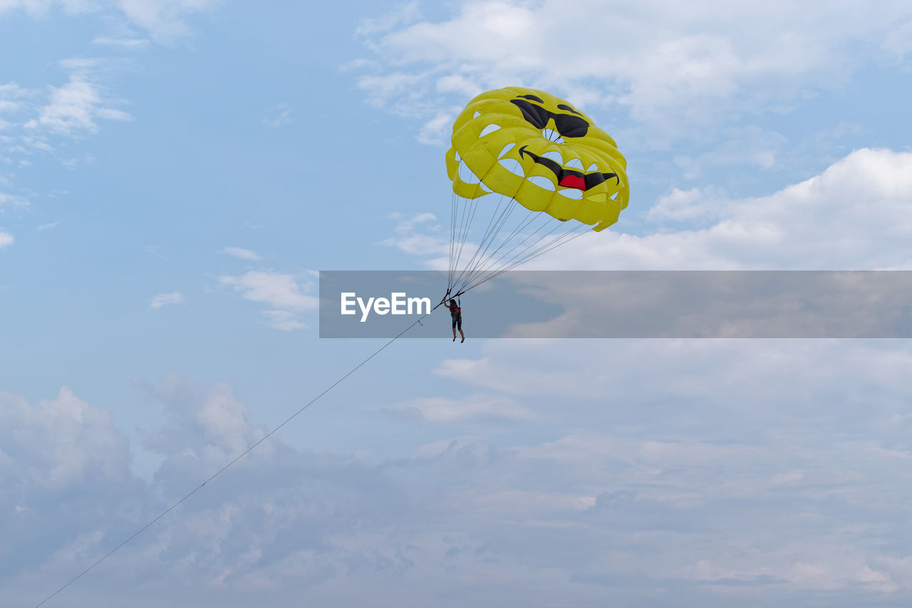 LOW ANGLE VIEW OF PERSON FLYING KITE