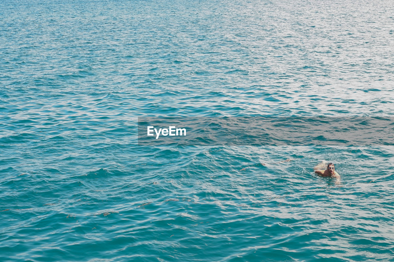 HIGH ANGLE VIEW OF MAN SWIMMING UNDERWATER