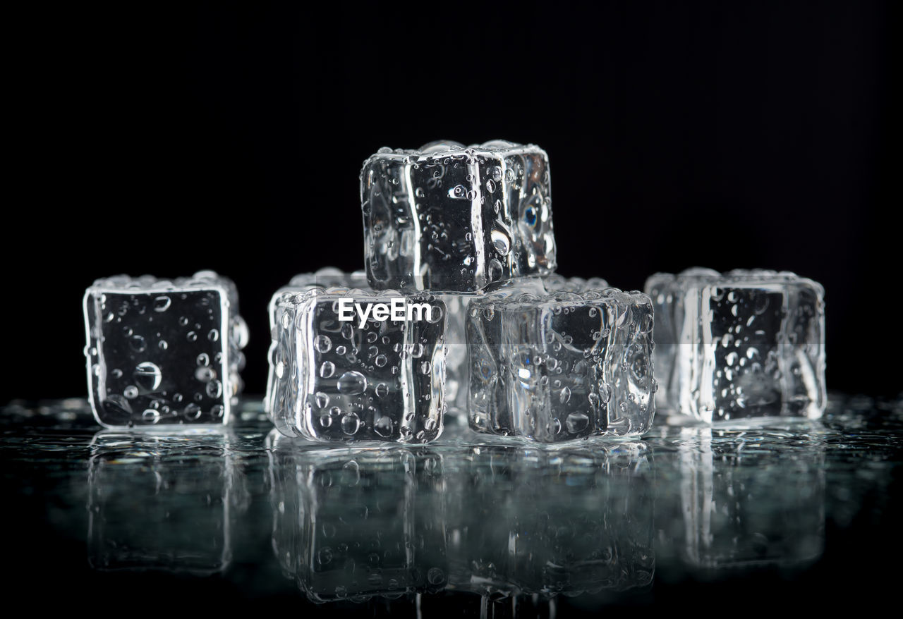 CLOSE-UP OF ICE CUBES IN GLASS AGAINST BLACK BACKGROUND