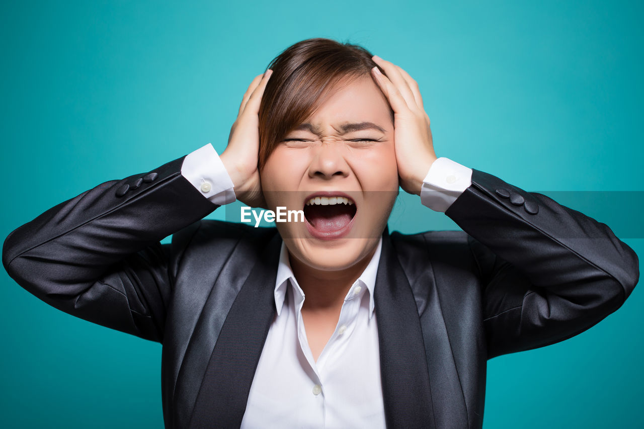 Portrait of frustrated businesswoman against blue background