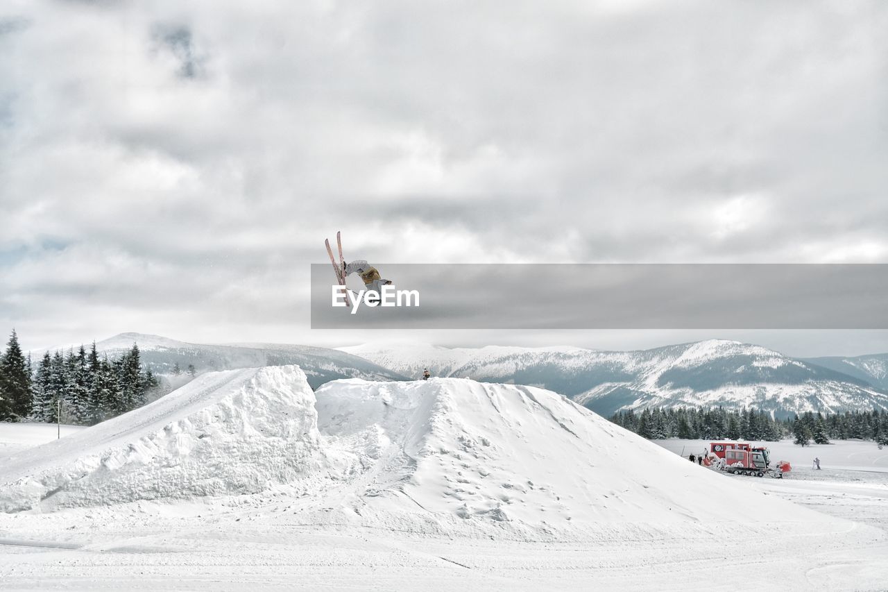 Man performing stunt while skiing on snowcapped mountain