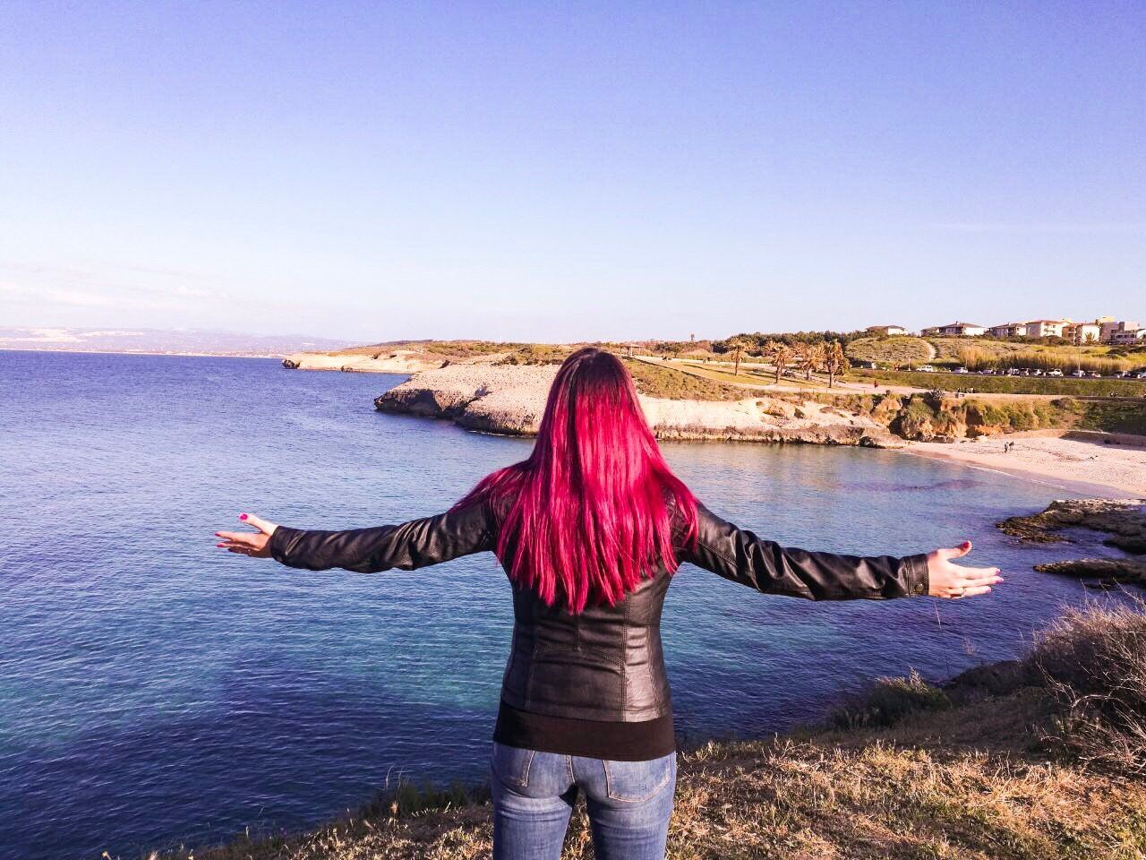 REAR VIEW OF WOMAN STANDING AGAINST SEA