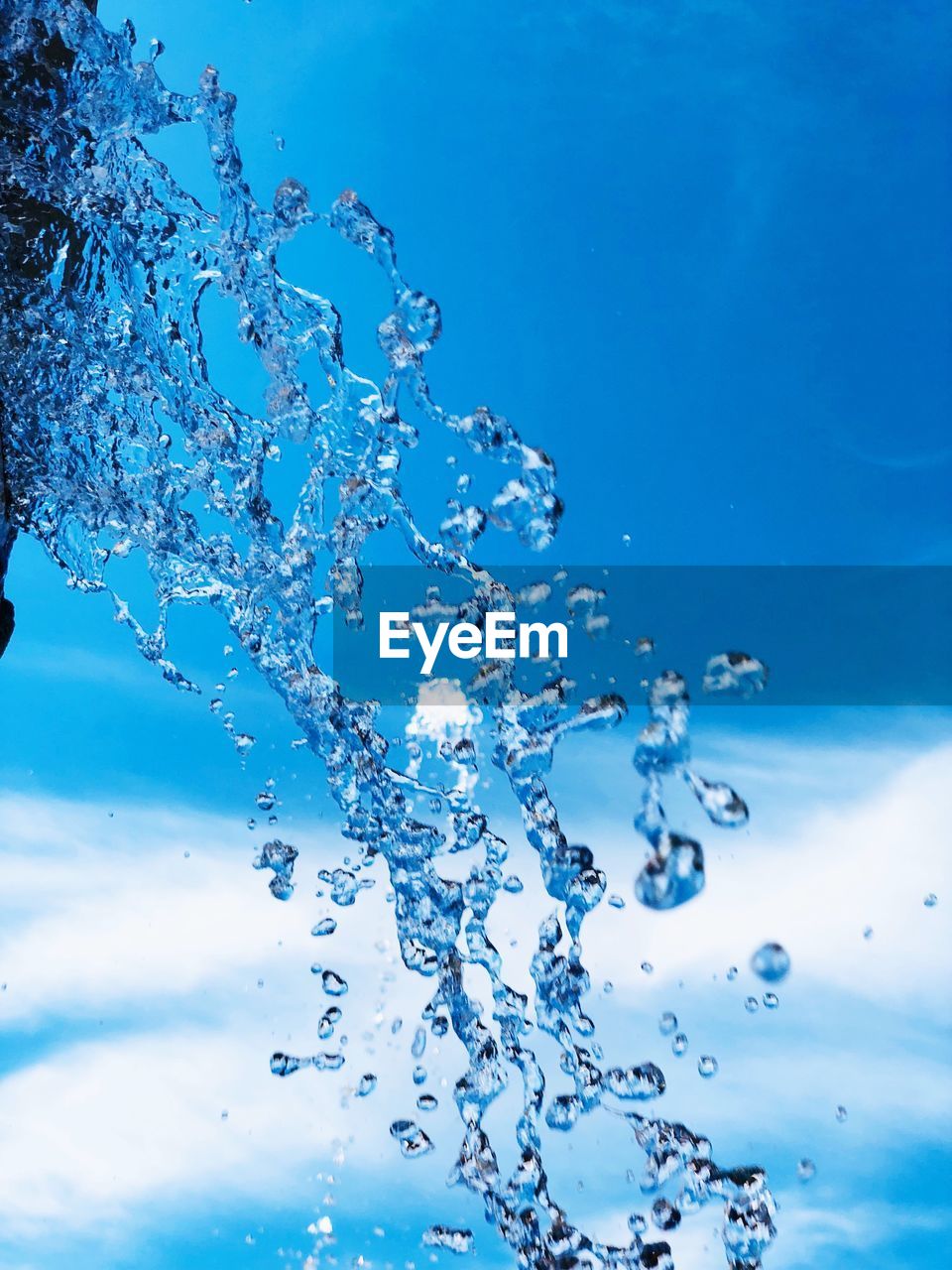 Close-up of water splashing against blue sky