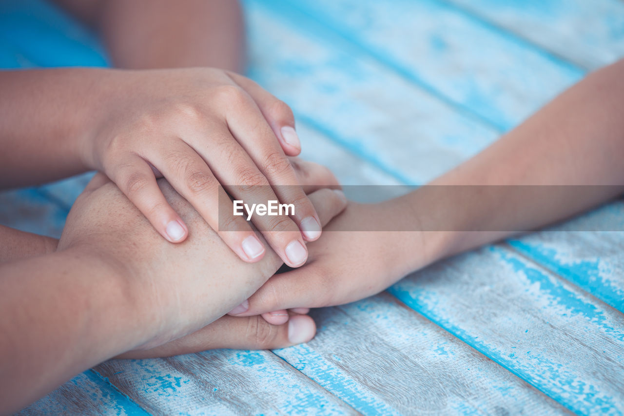 Cropped image of friends stacking hands on table