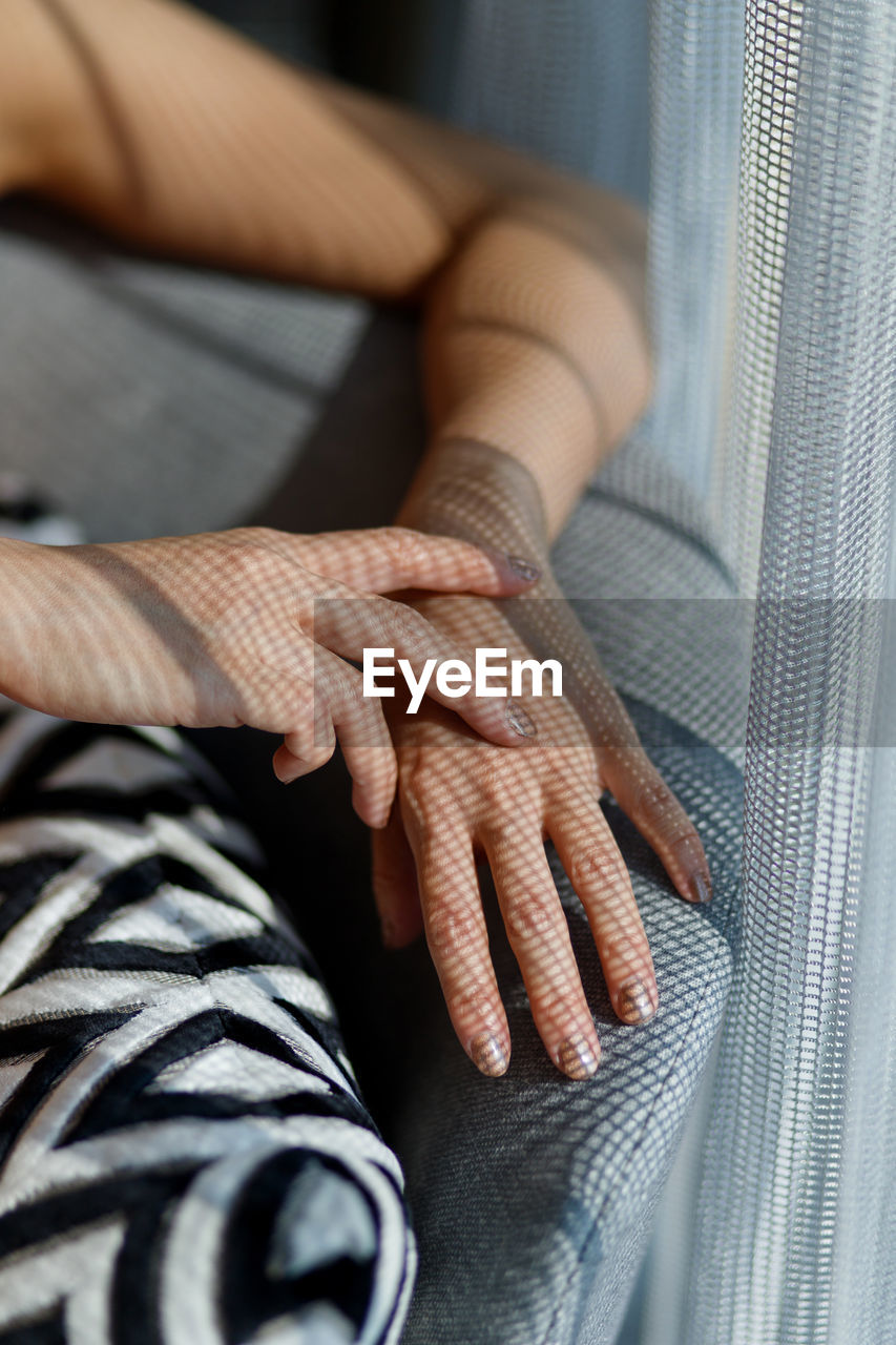 Cropped hands of woman relaxing on sofa at home