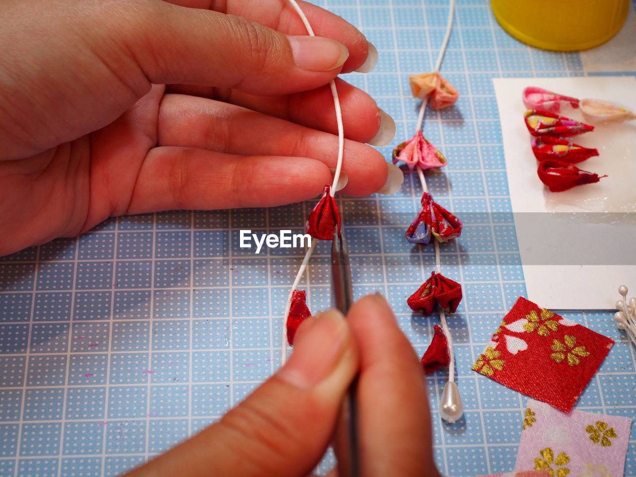 Cropped hands making fabric artwork at table