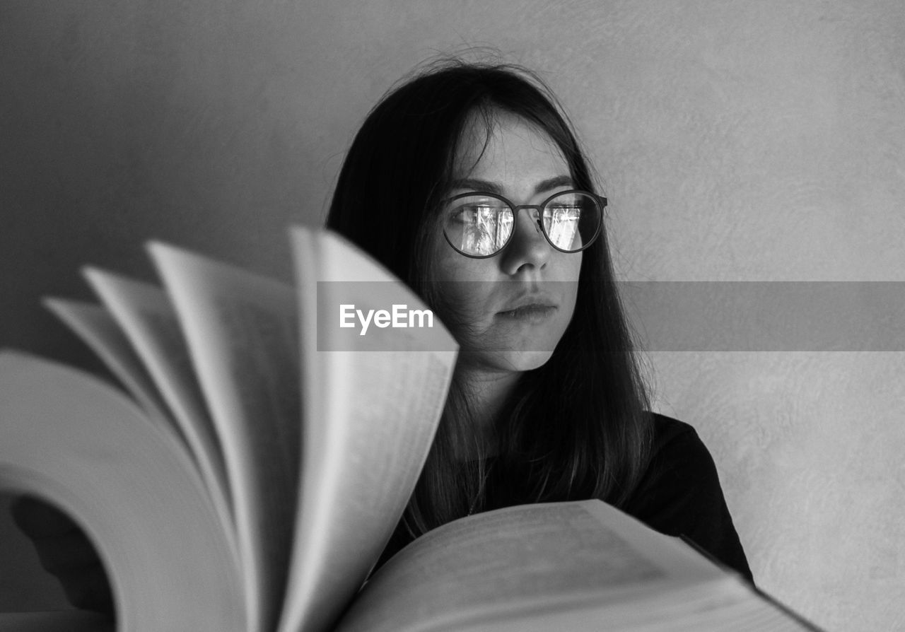 Thoughtful young woman by book looking away