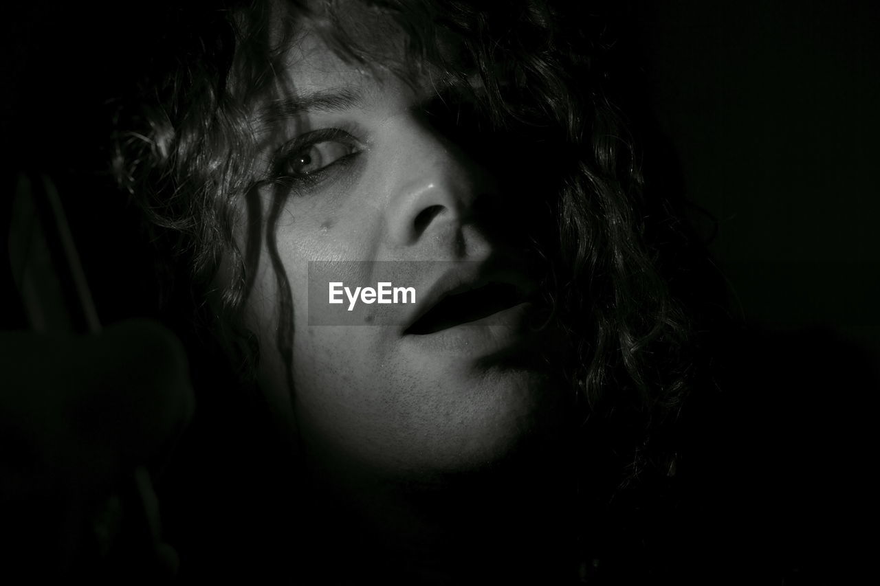 Close-up of thoughtful man against black background