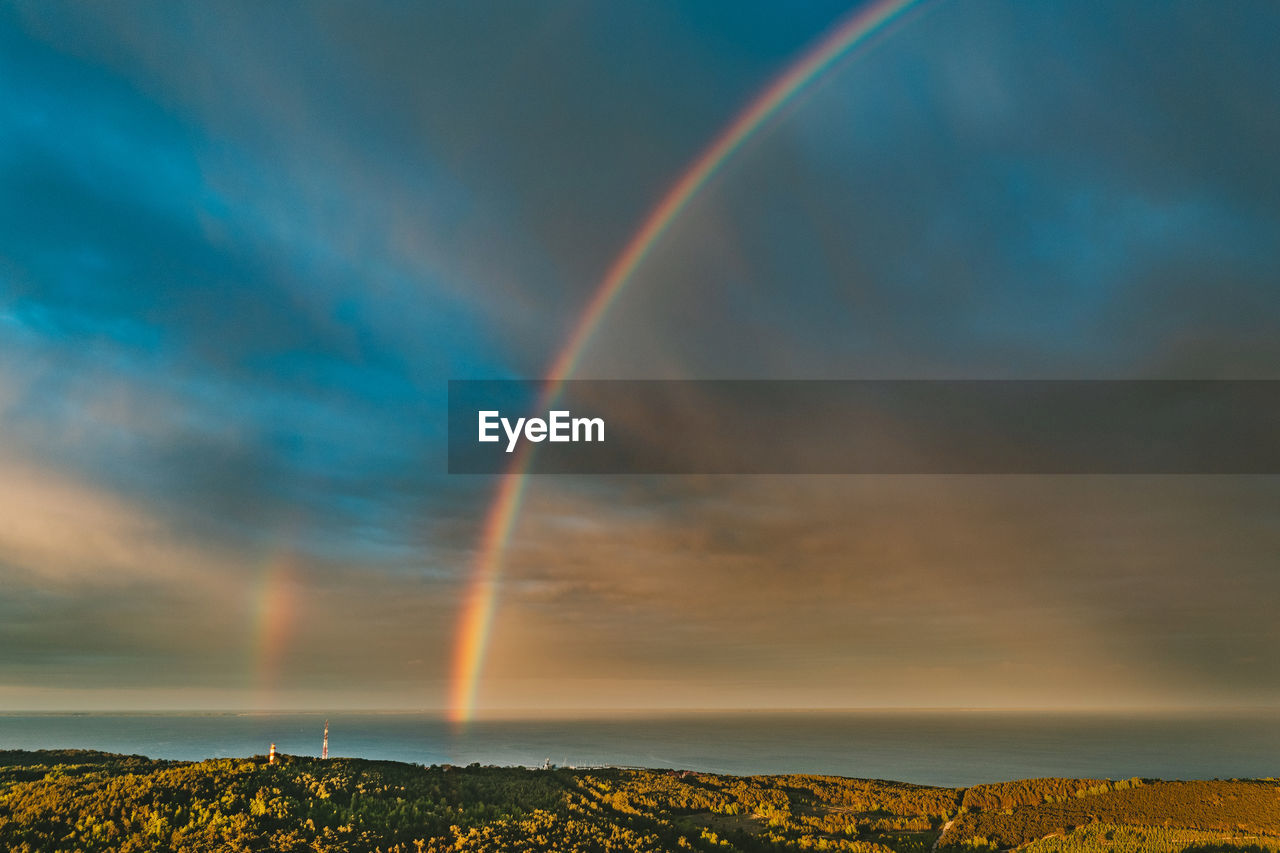 Scenic view of rainbow over sea against sky