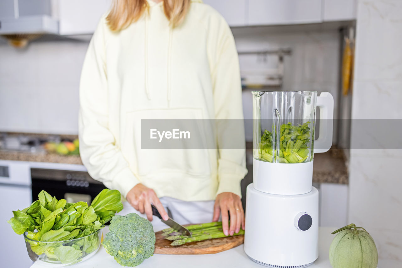 Midsection of woman standing in kitchen at home