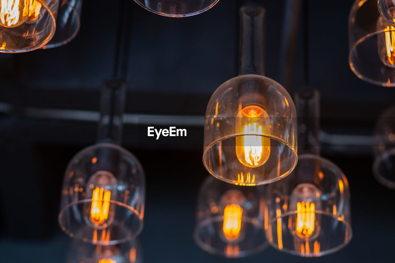 Close-up of illuminated light bulbs hanging from ceiling