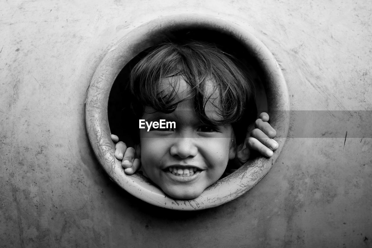 Close-up portrait of cute boy looking through circle at playground