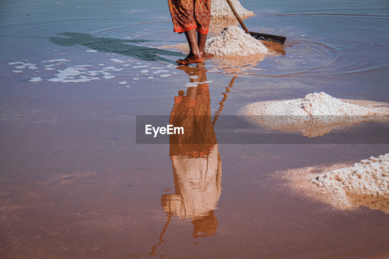 Low section of woman working whiel standing at salt flat