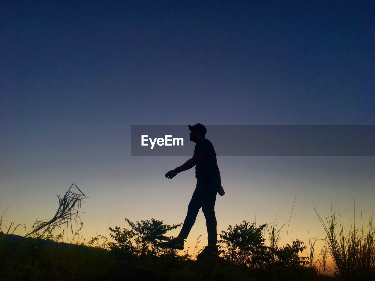 Silhouette man standing on field against sky during sunset