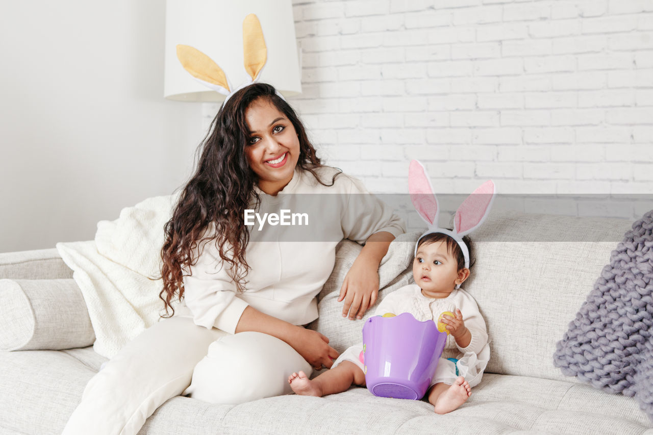 Mother and daughter sitting on sofa at home