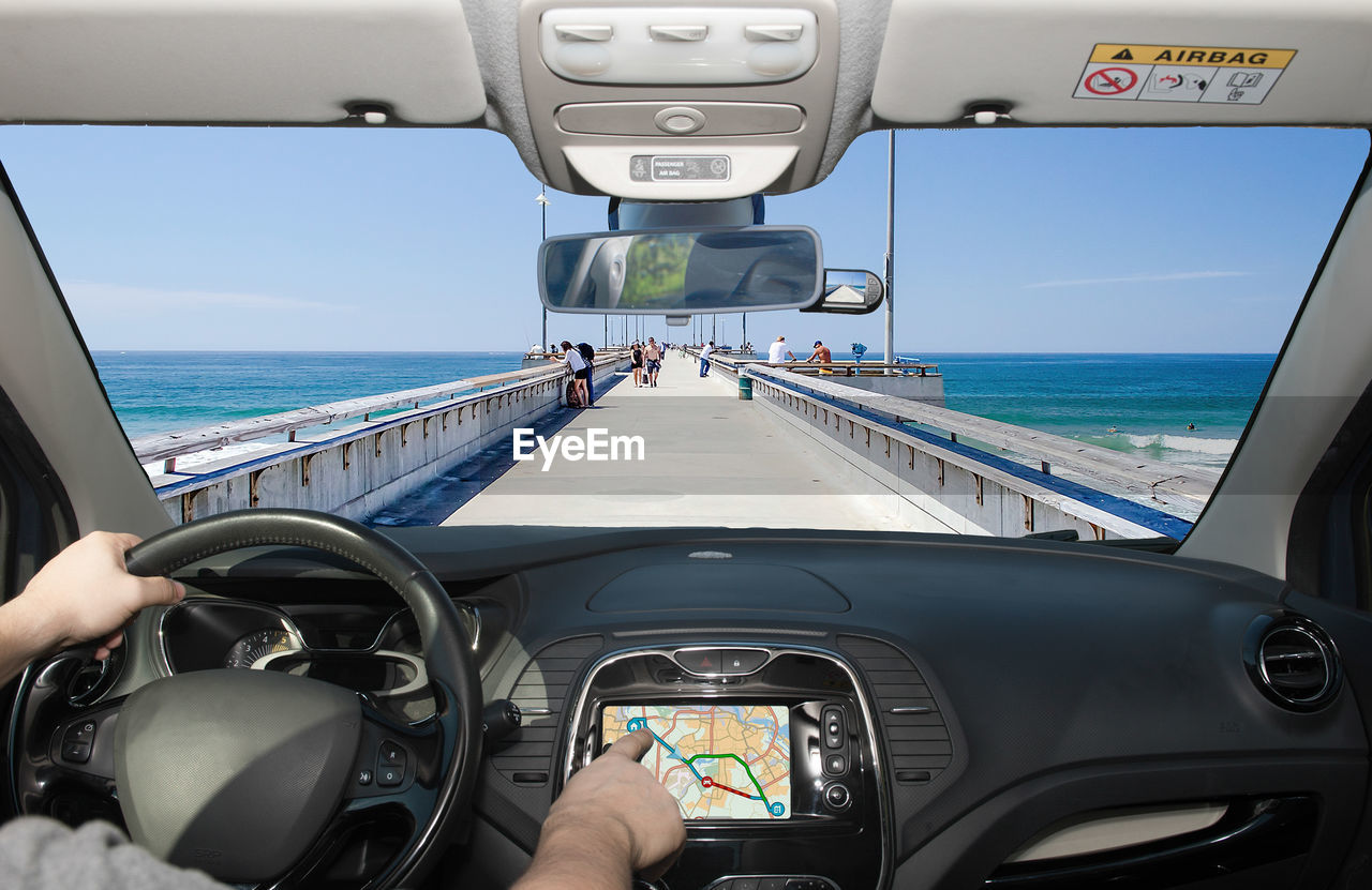 Cropped hand of man driving car on pier