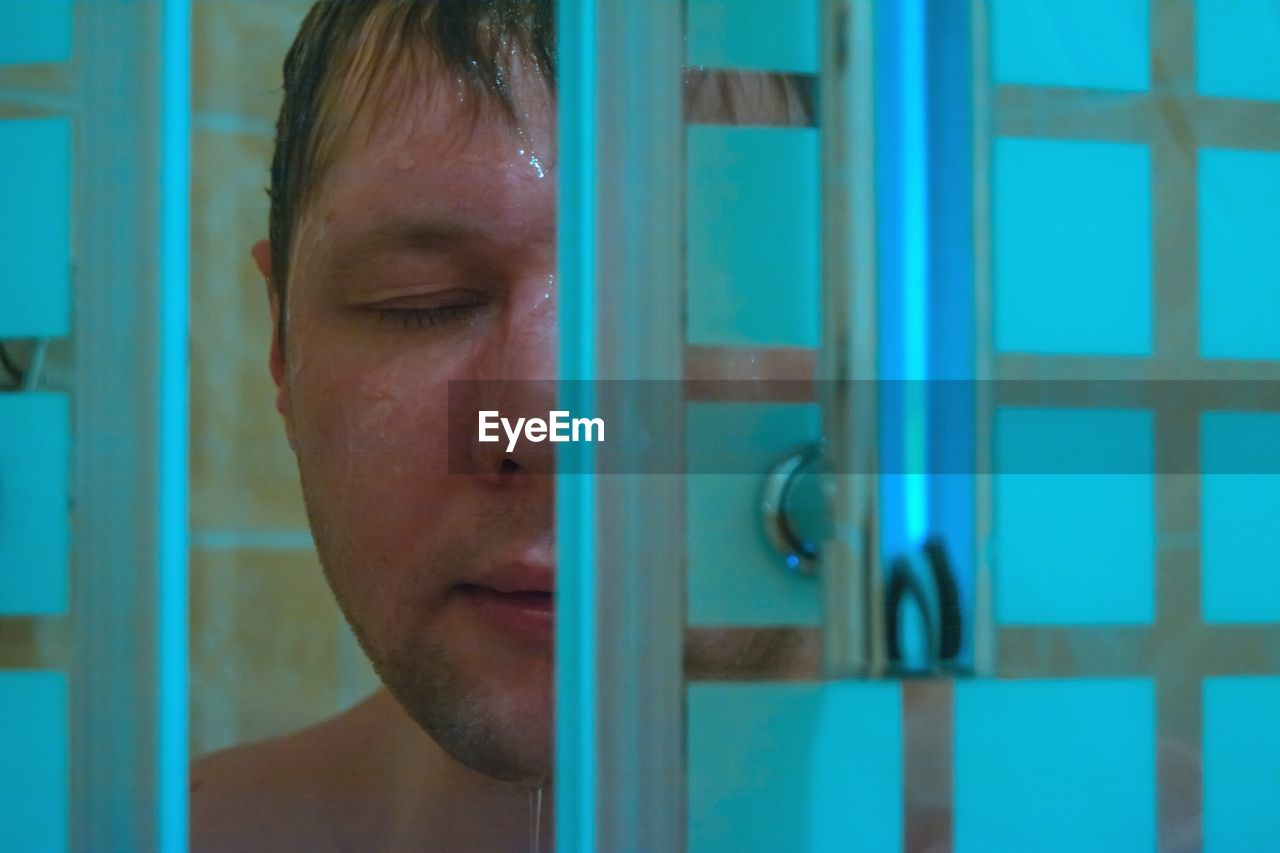 Close-up of mid adult man bathing seen through doorway