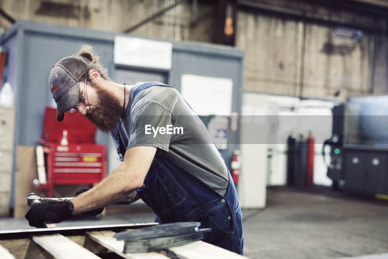 Manual worker using hammer and chisel in steel factory