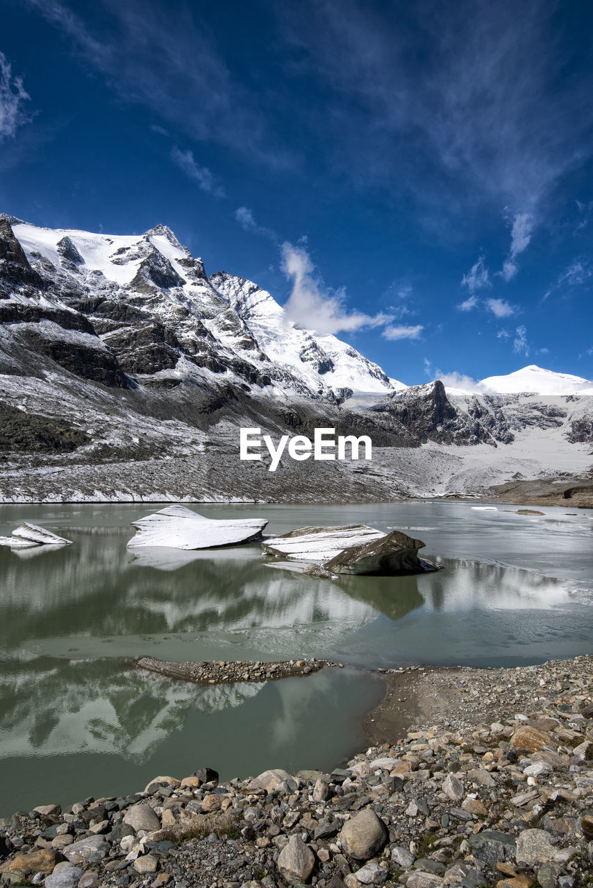 Scenic view of lake by snowcapped mountains against sky