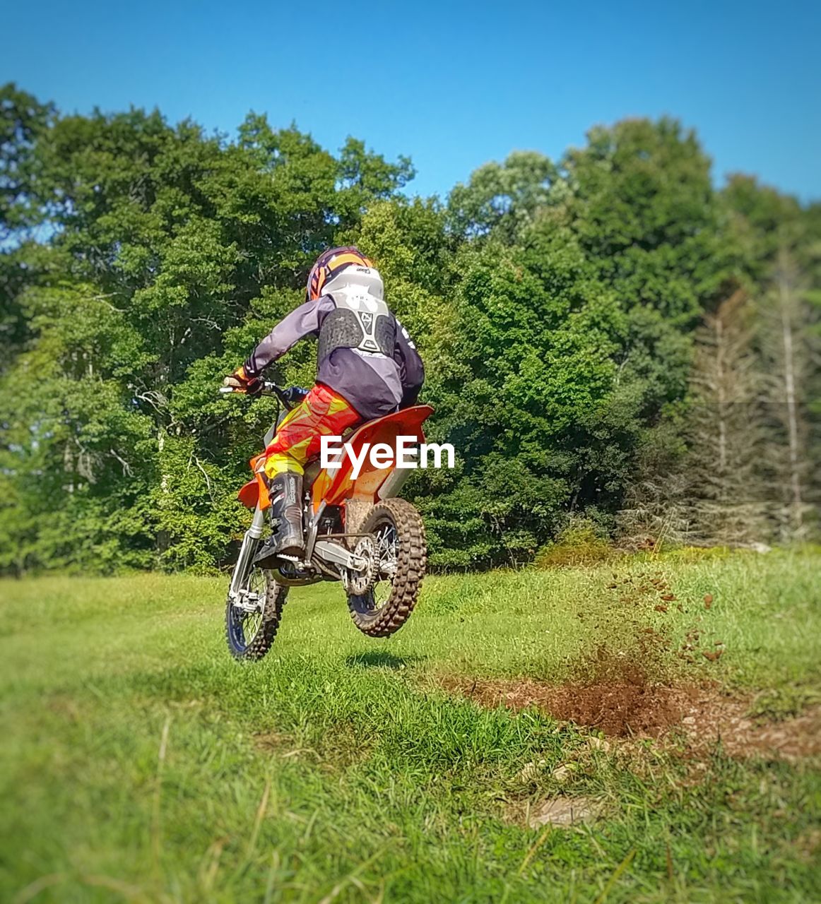 Child jumping motorcycle on field against sky