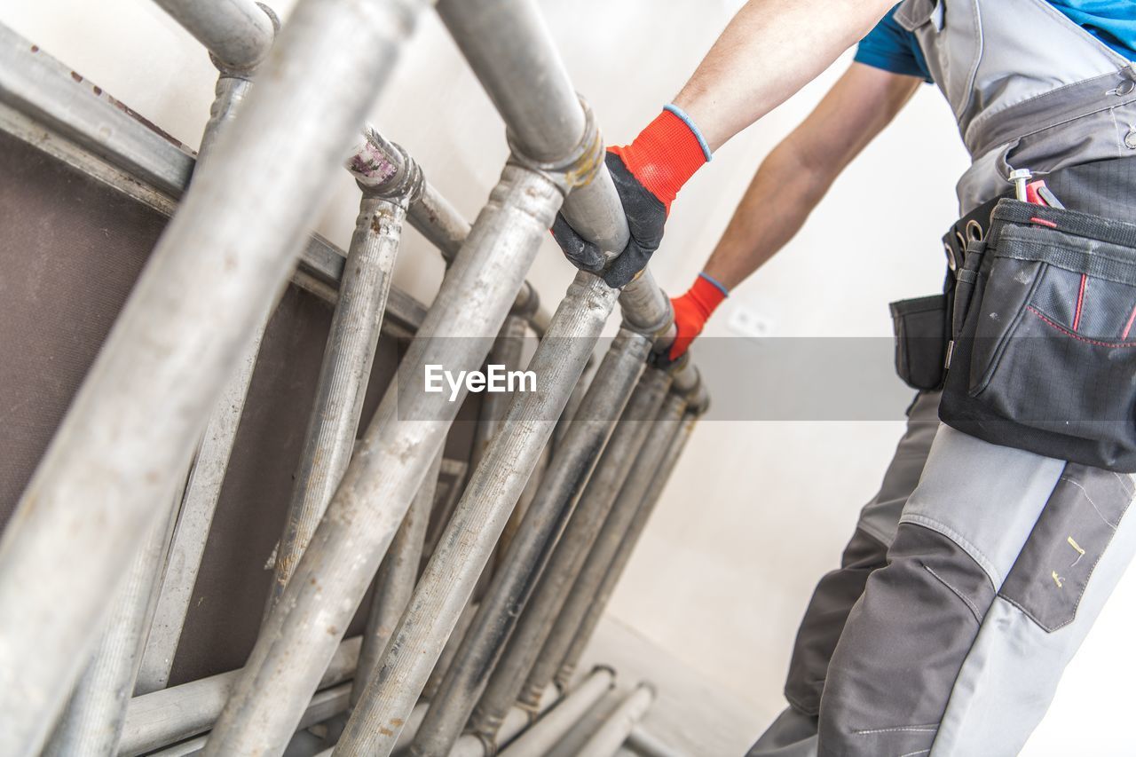 LOW ANGLE VIEW OF PERSON WORKING ON METAL STRUCTURE