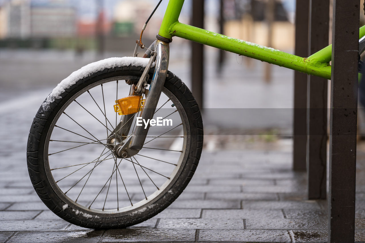 CLOSE-UP OF BICYCLE WHEEL BY RAILING