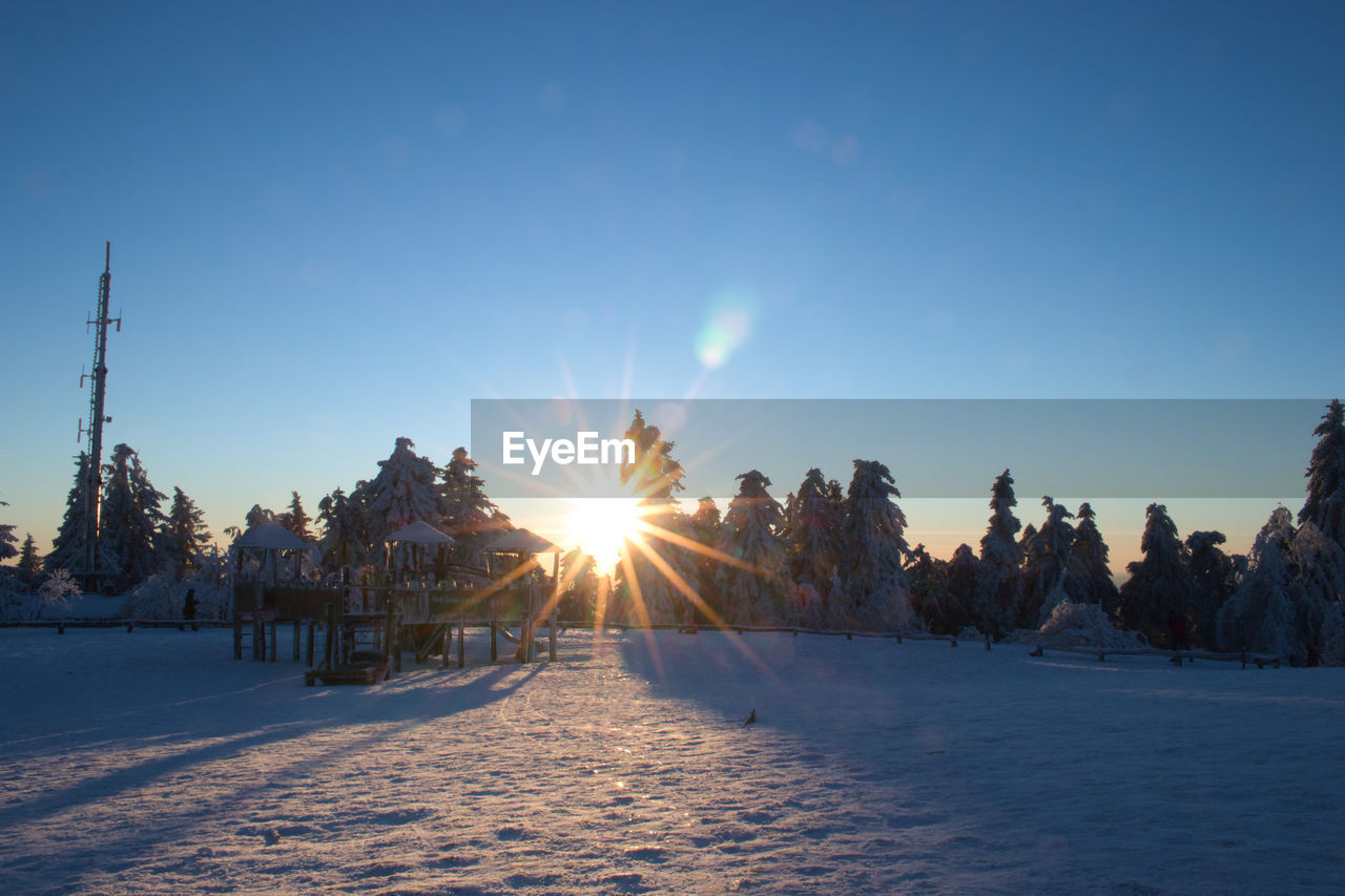 SNOW COVERED LAND AGAINST SKY AT SUNSET