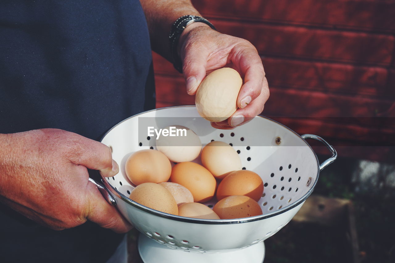 Midsection of man holding egg in container