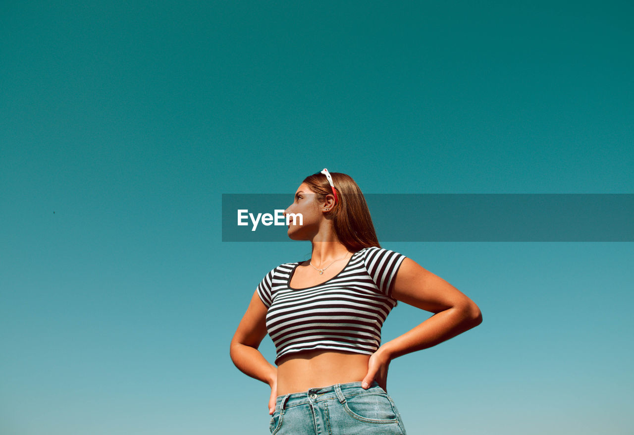 WOMAN STANDING AGAINST BLUE SKY