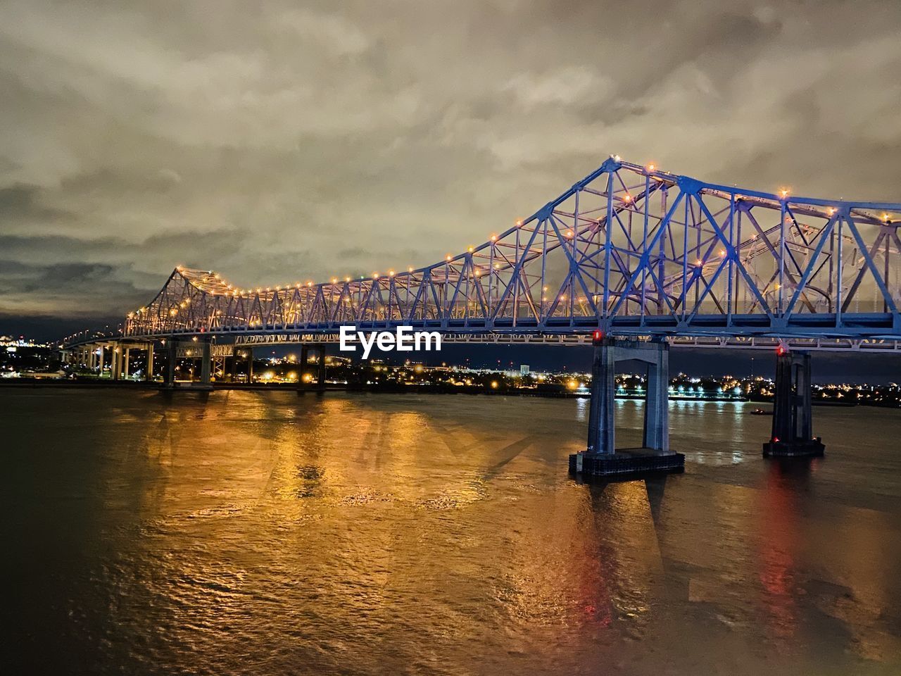 Illuminated bridge over river against sky at dusk