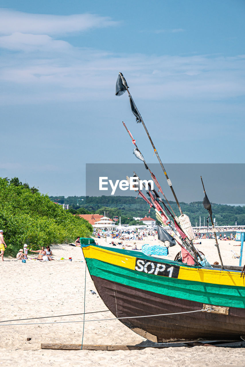 BOAT MOORED ON SHORE AGAINST SKY