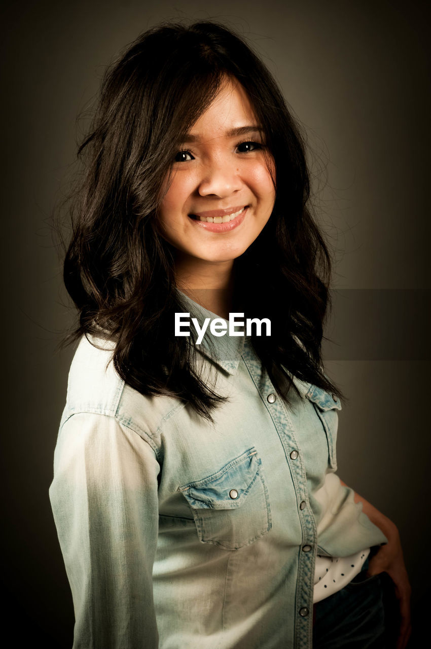 portrait, smiling, one person, portrait photography, looking at camera, studio shot, happiness, long hair, hairstyle, women, emotion, female, indoors, photo shoot, adult, cheerful, person, white, waist up, child, black, young adult, smile, brown hair, teeth, teenager, casual clothing, positive emotion, human face, front view, childhood, clothing, standing, cute, headshot, individuality, cut out, black background, fashion, black hair, joy