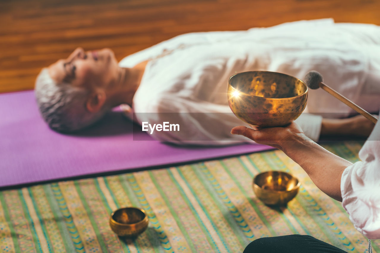 Cropped hands of woman playing singing bowl for customer in spa