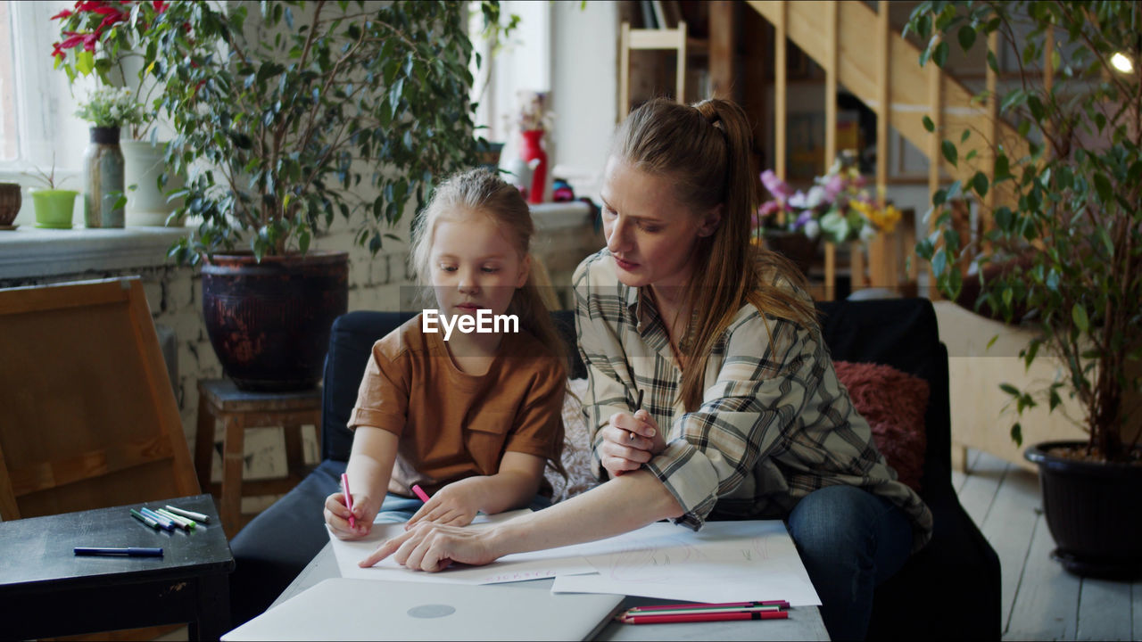 Mother teaching daughter at home