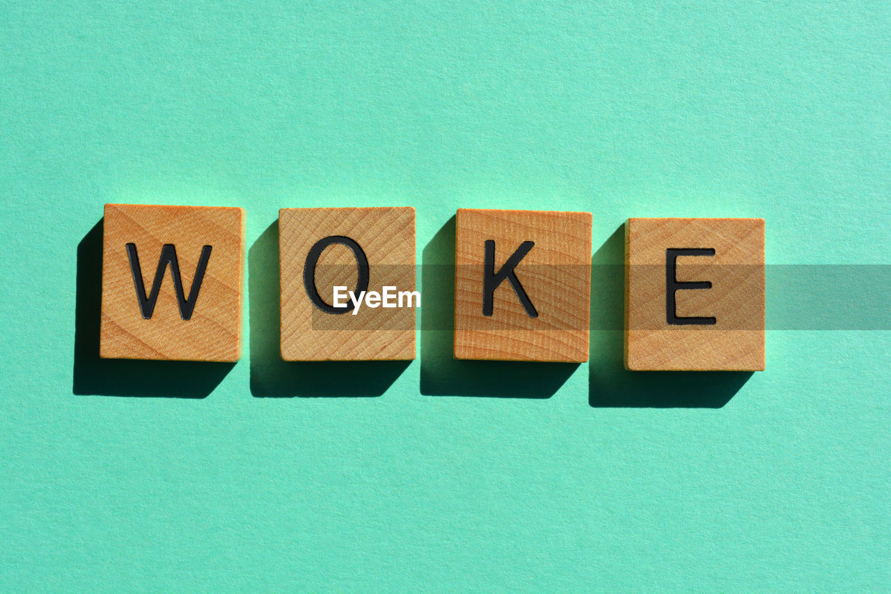 Woke, word in wooden alphabet letters isolated on turquoise background