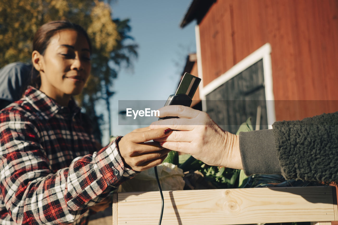 Mature woman paying female farmer through credit card at market